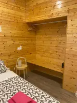 Habitación Doble Confort con dos camas individuales y apliques sobre una pared de madera de pino